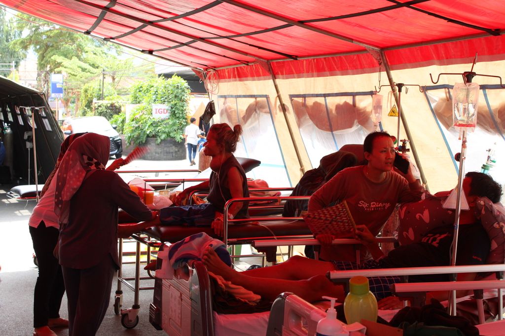 Sejumlah pasien bertahan di tenda darurat yang dipasang di depan Rumah Sakit Umum Daerah Sumedang, Kabupaten Sumedang, Jawa Barat, Senin (1/1/2024). Para pasien dirawat secara darurat di luar rumah sakit setelah terjadi gempa sehari sebelumnya.