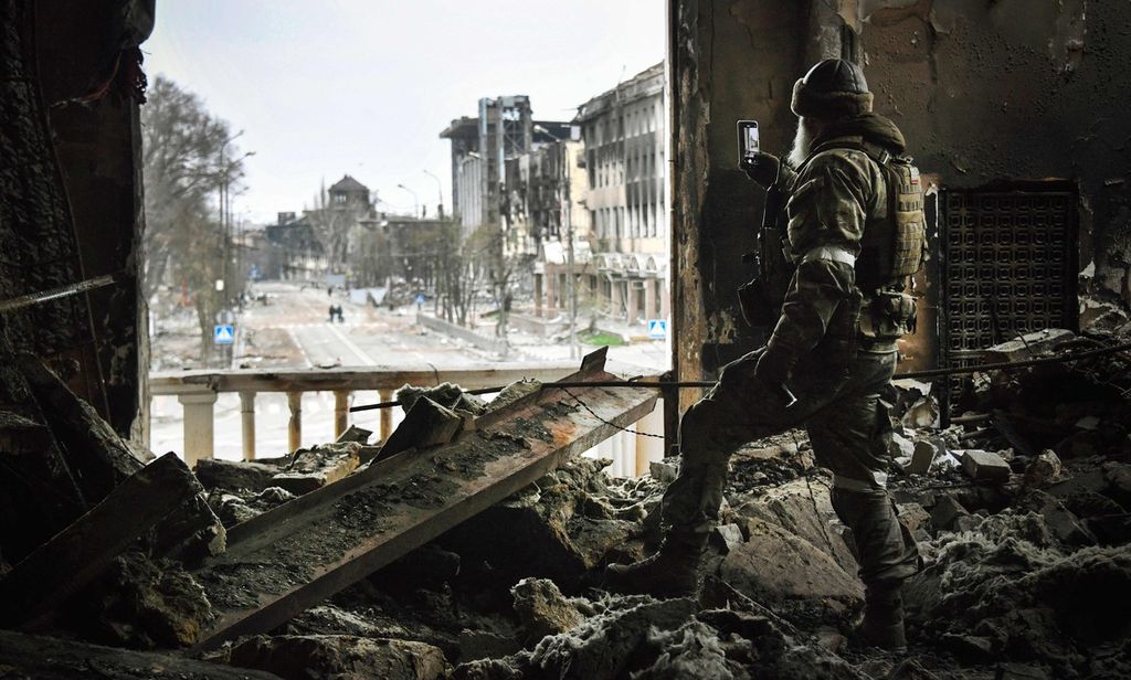 Seorang tentara Rusia pada 12 April 2022 berpatroli di gedung teater drama Mariupol, yang dibom pada 16 Maret 2022, Foto ini dibuat dalam perjalanan yang diatur oleh militer Rusia. 