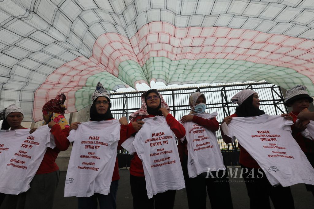 Sejumlah peserta unjuk rasa membawa kaus bertuliskan aspirasi mereka dalam aksi memperingati Hari Pekerja Rumah Tangga di depan kompleks Gedung Parlemen, Jakarta, Rabu (15/2/2023). 