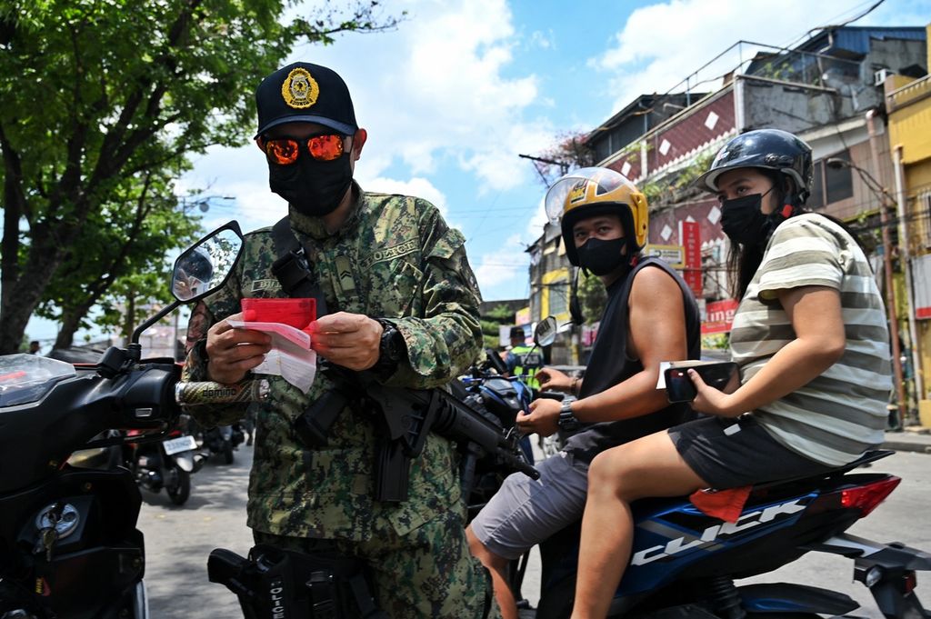 Seorang polisi memeriksa kartu identitas penduduk seorang pengendara sepeda motor di pusat kota Manila, Filipina, Rabu (4/5/2022). Polisi Filipina menurunkan 12000 personel untuk pengamanan pemungutan suara, Senin (9/5/2022). 