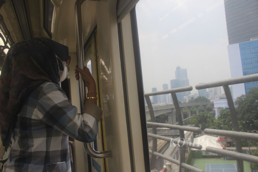 Seorang penumpang LRT Jabodebek melihat pemandangan di luar ketika kereta melaju, Senin (11/9/2023). 
