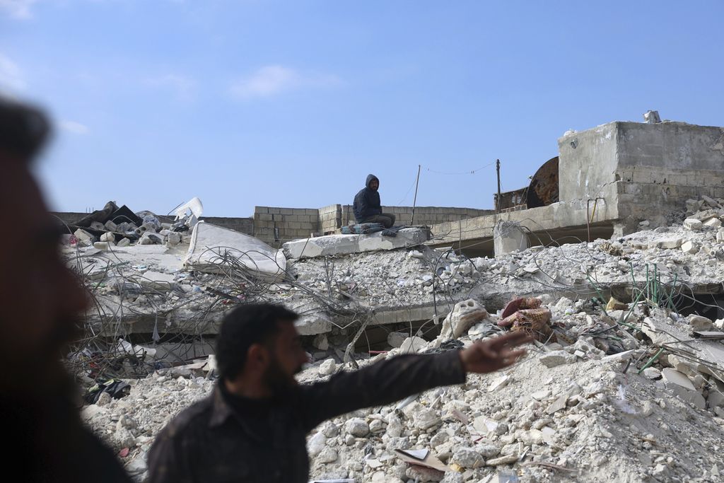 Seorang pria duduk di atas reruntuhan bangunan yang ambruk akibat gempa di kota Jinderis, Provinsi Aleppo, Suriah, 14 Februari 2023. 