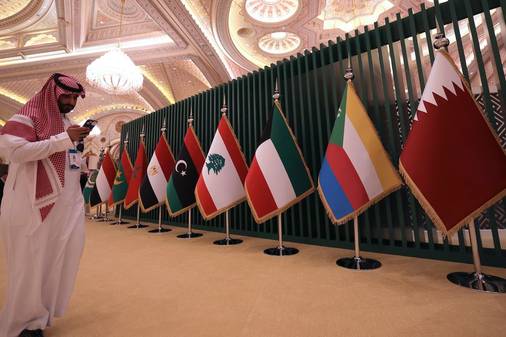 Warga Arab Saudi berdiri di dekat deretan bendera negara-negara dalam kegiatan Konferensi Bisnis China-Arab, di Riyadh, Minggu (11/6/2023). 