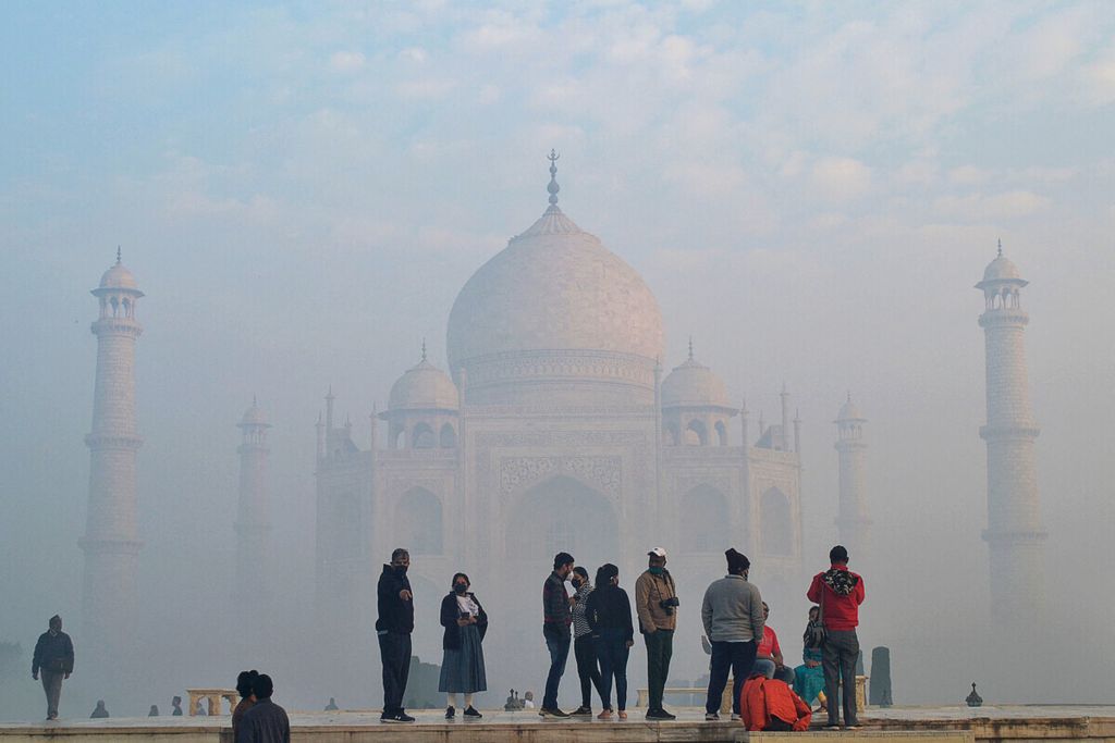 Wisatawan saat menikmati suasana kompleks Taj Mahal yang berkabut pada 4 Januari 2022. Kunjungan wisatawan internasional baru akan pulih secara global sepenuhnya tahun 2024.