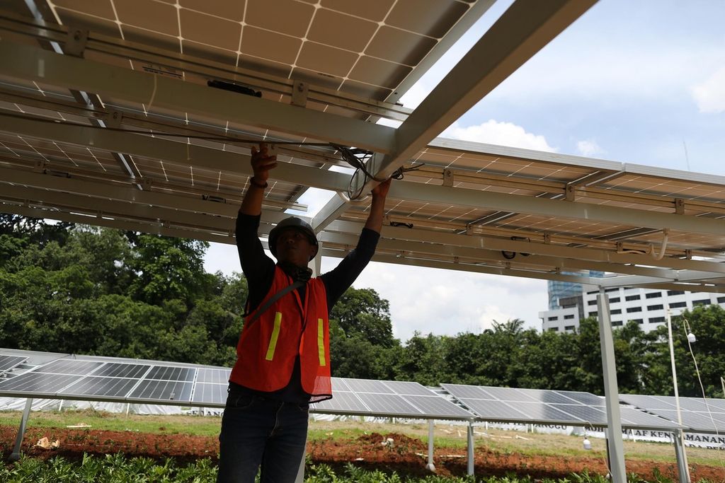 Pekerja menyelesaikan pemasangan surya panel di halaman kompleks Parlemen, Jakarta, Senin (13/12/2021). 