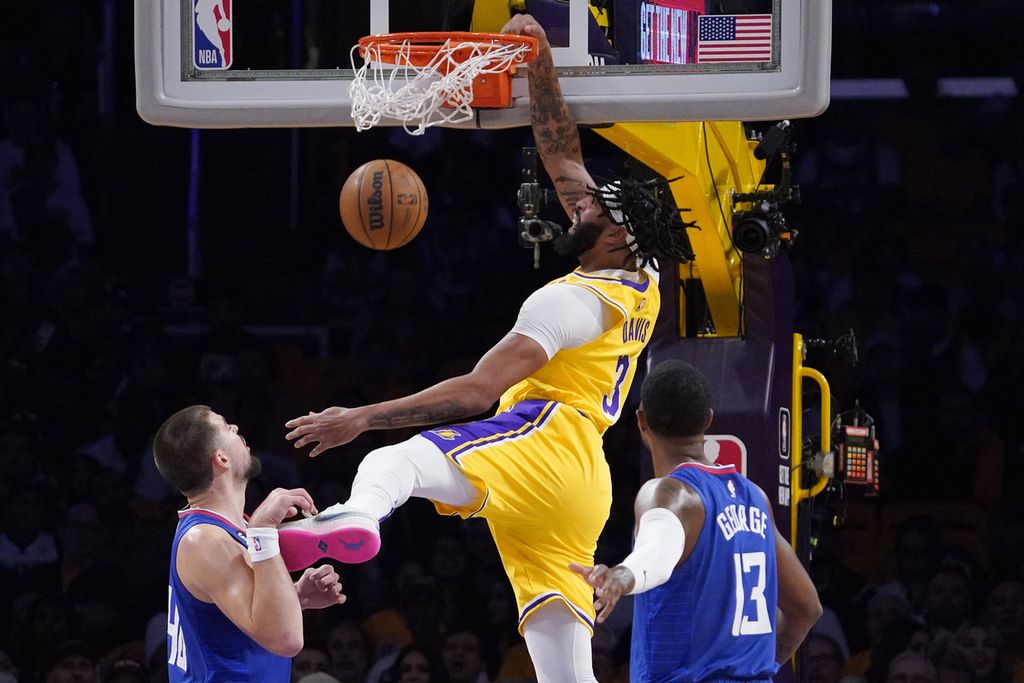 <i>Forward</i> Los Angeles Lakers, Anthony Davis (tengah), melakukan <i>dunk</i> untuk memasukkan bola melewati <i>center</i> Los Angeles Clippers, Ivica Zubac, dan <i>guard</i> Paul George dalam pertandingan NBA antara LA Lakers dan LA Clippers di Arena Crypto.com, Jumat (21/10/2022) WIB. Clippers mengalahkan Lakers, 103-97. 