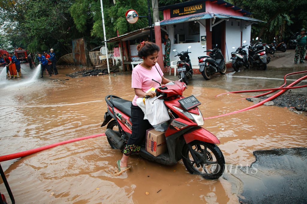 Pengendara sepeda motor melintas genangan air di jalan perumahan Ciledug Indah 1, Karang Tengah, Kota Tangerang, Banten, Minggu (17/7/2022).