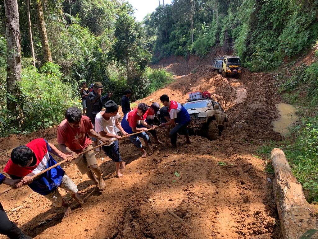 Petugas Pertamina membantu menarik kendaraan warga yang terjebak dalam kubangan lumpur di Seko, Kabupaten Luwu Utara, Sulawesi Selatan, September 2021. Jalur ini menjadi salah satu jalur distribusi program BBM Satu Harga.
