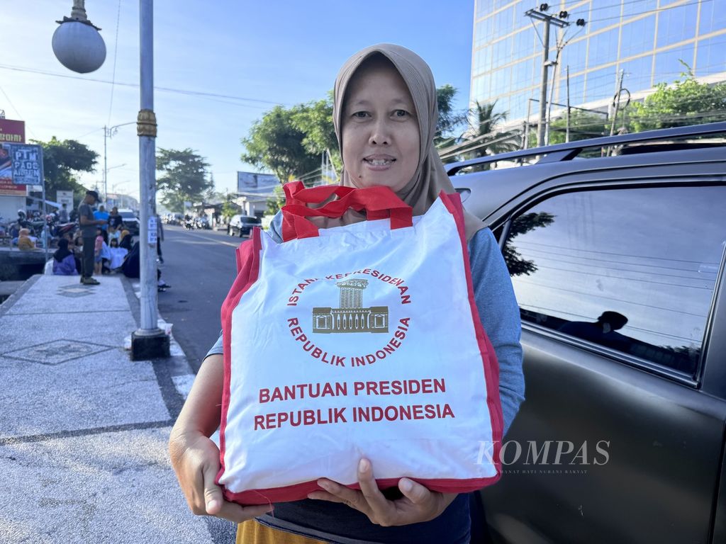 Hayani (43), warga Kota Mataram, memperlihatkan tas berisi sembako bantuan Presiden Joko Widodo, Rabu (1/5/2024) pagi.