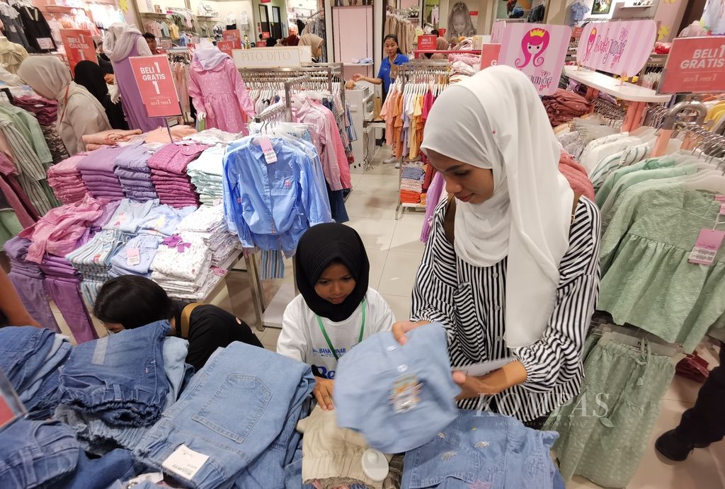 Seorang anak didampingi ibunya memilih baju lebaran di Lombok Epicentrum Mall di Mataram, Nusa Tenggara Barat, Minggu (9/4/2023). Konsumsi rumah tangga cenderung menurun pada 2023. 