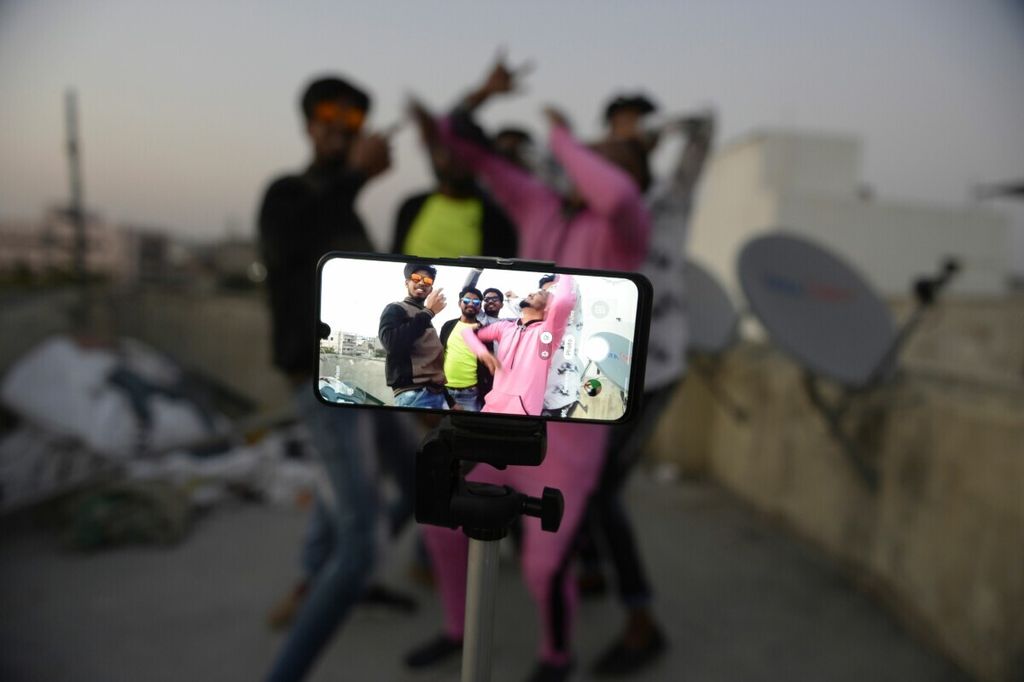Anak-anak muda beraksi di depan kamera gawai saat membuat video TikTok di teras rumah mereka di Hyderabad, India, 14 Februari 2020. 