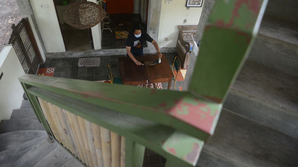 Pemilik homestay Rubilang Desi Suryanto membersihkan ruang tamu bagi penginap di homestay miliknya di Desa Bangunjiwo, Kasihan, Bantul, DI Yogyakarta, Minggu (22/8/2021). Okupasi di homestay tersebut turun drastis akibat pandemi.