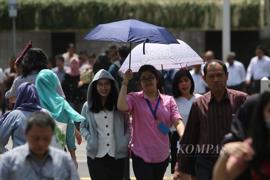 Sejumlah warga menggunakan payung saat beraktivitas di luar ruang di kawasan Bundaran Hotel Indonesia, Jakarta Pusat, karena cuaca yang terik, Senin (21/10/2019).