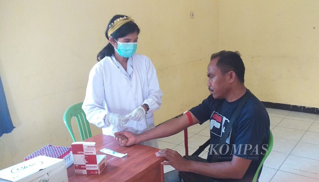 Ign (34), salah satu tukang parkir di Pasar Oeba, Kupang, sedang diambil darahnya oleh petugas kesehatan  Puskesmas Fatuleu Kupang untuk tes HIV, Kamis (1/12/2022).