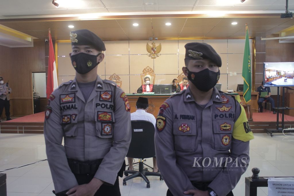 Two police officers escort the trial of the sexual violence case against a dozen students in Bandung, by the defendant Herry Wirawan, at the Bandung Special Class 1A District Court, West Java, Tuesday (15/2/2022).).
