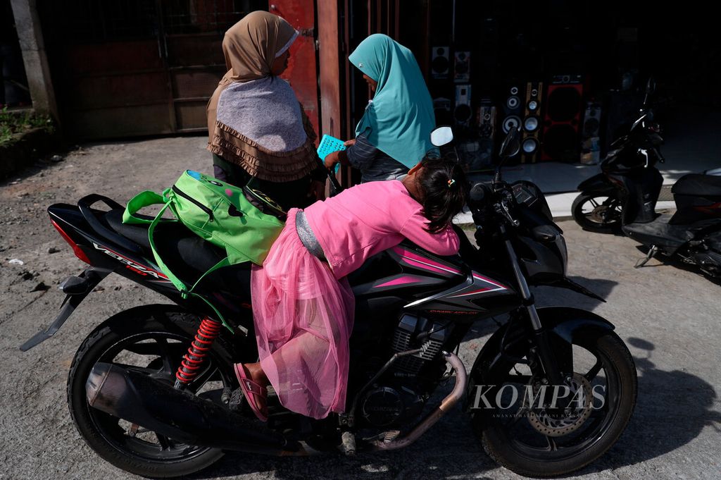 Anak-anak tidur di atas motor saat menunggu orangtuanya belanja kebutuhan harian di Pasar Kaponan di Kecamatan Pakis, Kabupaten Magelang, Jawa Tengah, Senin (4/7/2022). 