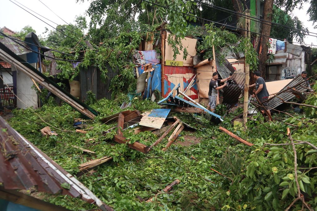 Petugas membereskan atap sejumlah warung yang berantakan akibat  tertimpa pohon tumbang di Jalan Cipto Mangunkusumo, Kota Cirebon, Jawa Barat, Sabtu (4/12/2021). Angin kencang dan hujan deras pada Jumat (3/12) malam menyebabkan pohon tumbang di sejumlah daerah di Cirebon.