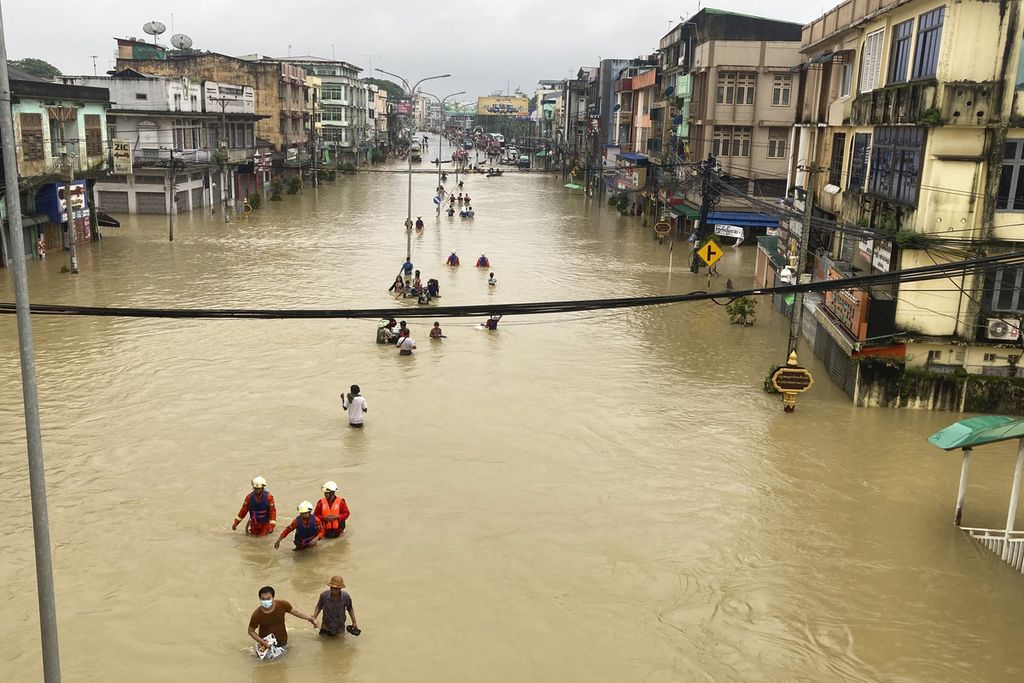 Sukarelawan penyelamat dan warga setempat menyeberangi jalan yang banjir di Bago, sekitar 80 kilometer timur laut Yangon, Myanmar, Selasa, 10 Oktober 2023. 