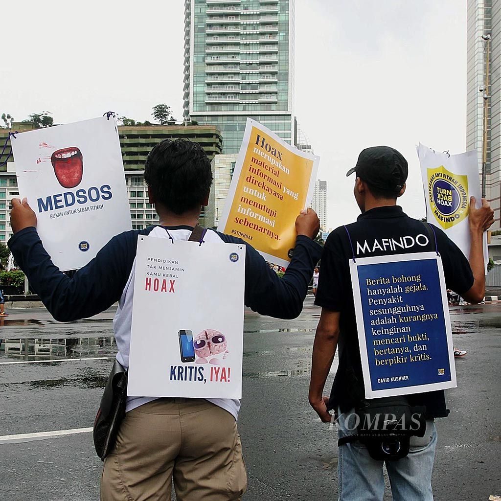 Sejumlah aktivis   Masyarakat Anti Fitnah Indonesia  membawa pamflet untuk mengingatkan warga atas  berita bohong alias hoaks, Minggu (12/2), di Jakarta. 