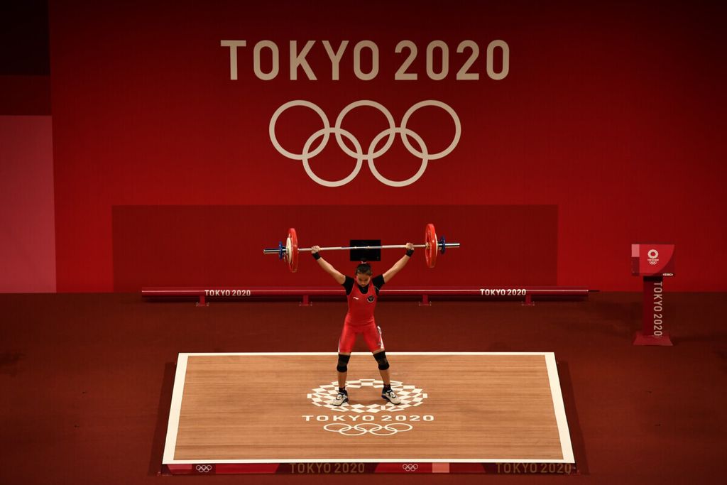 Lifter putri Indonesia Windy Cantika Aisah melakukan angkatan <i>snatch</i> dalam kelas 49 kg putri Grup A Olimpiade Tokyo 2020 di Tokyo International Forum, Tokyo, Jepang, Sabtu (24/7/2021). Windy berhasil mempersembahkan medali pertama bagi Indonesia, yakni perunggu, dengan total angkatan 194 kg.
