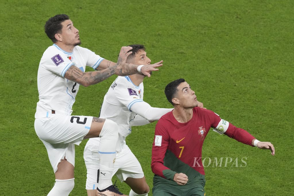 Pemain Portugal Cristiano Ronaldo (kanan) dijaga pemain Uruguay saat bertanding di fase Grup H Piala Dunia 2022 di Stadion Education City, Qatar, Selasa (29/11/2022) dini hari WIB. 