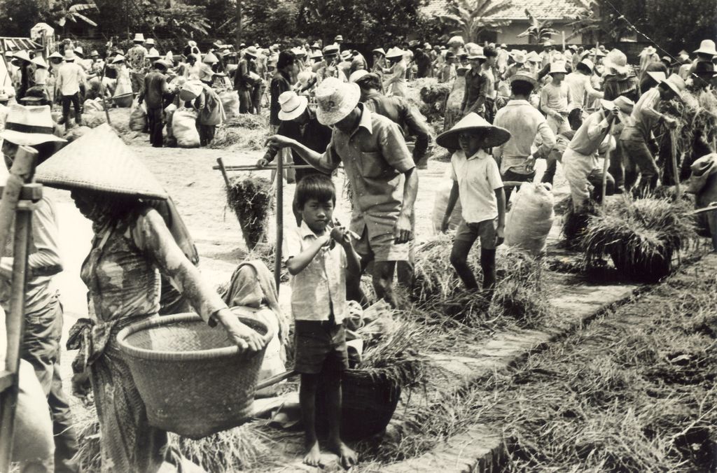Seusai panen padi di Karawang, Jawa Barat, para buruh tani dengan riang gembira menanti bagian hasilnya Padi yang mereka terima tidak banyak karena enam bagian untuk pemilik sawah, sementara satu bagian dibagi ramai-ramai di antara pemanen. Foto diambil pada tahun 1984.