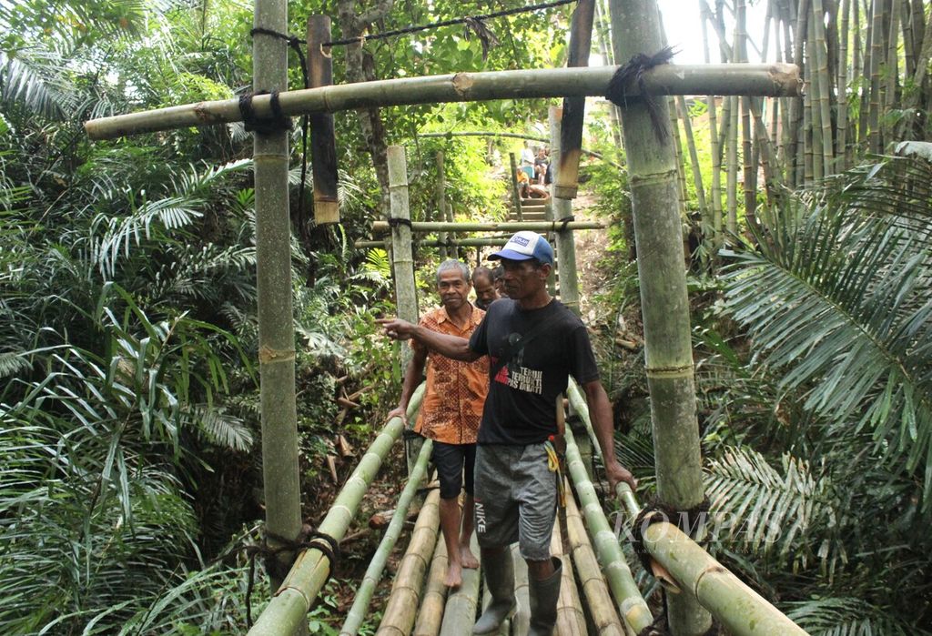 Sejumlah warga melintasi jembatan bambu di Desa Wolowea, Kabupaten Nagekeo, Nusa Tenggara Timur, Rabu (22/6/2022). Jembatan itu dibangun tanpa memakai paku, tetapi menggunakan pasak dan ijuk sebagai pengikat.