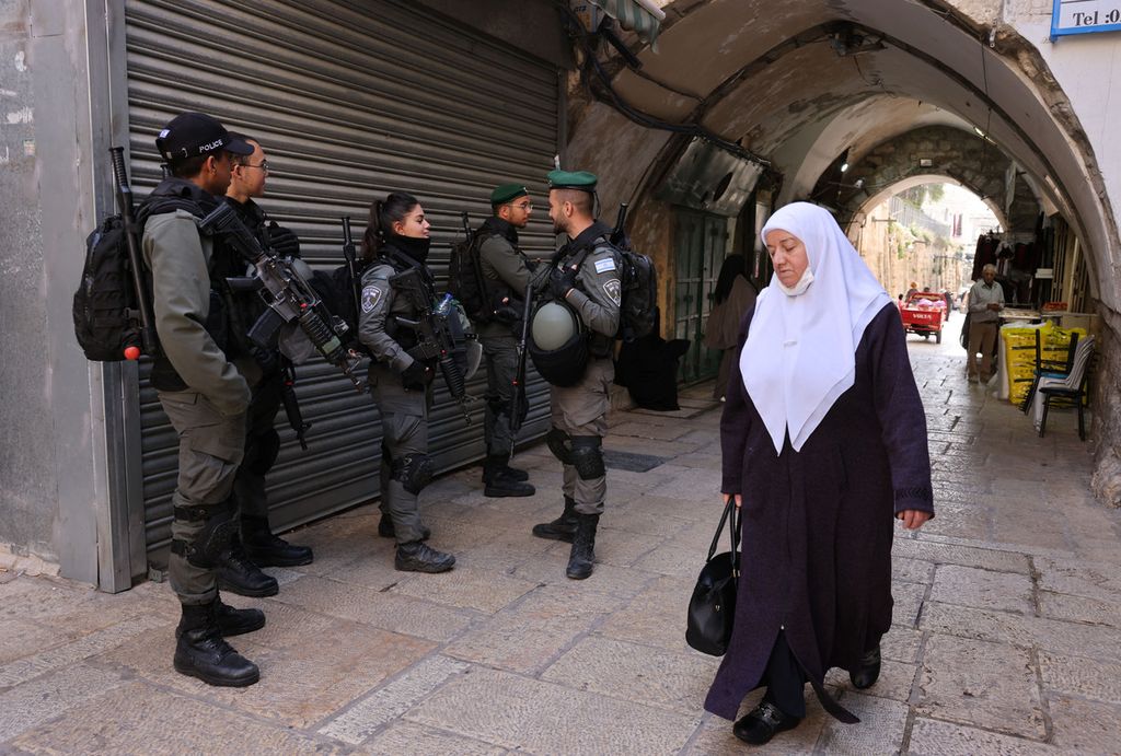 Perempuan Palestina berjalan melewati pasukan keamanan Israel di Kota Tua Jerusalem, 31 Maret 2022. 