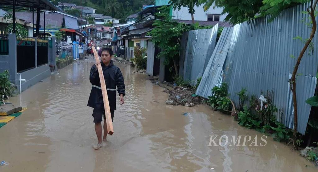 Warga membawa material sisa banjir bandang di Lorong Lasolo, Kendari, Sulawesi Tenggara, Selasa (12/3/2024). 