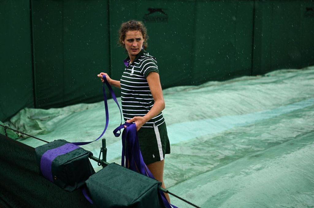 Staf panitia Wimbledon 2023 menarik tali pelindung lapangan saat turunnya hujan pada hari ketiga turnamen tenis bergengsi itu di All England Tennis Club di Wimbledon, Inggris, Rabu (5/7/2023).