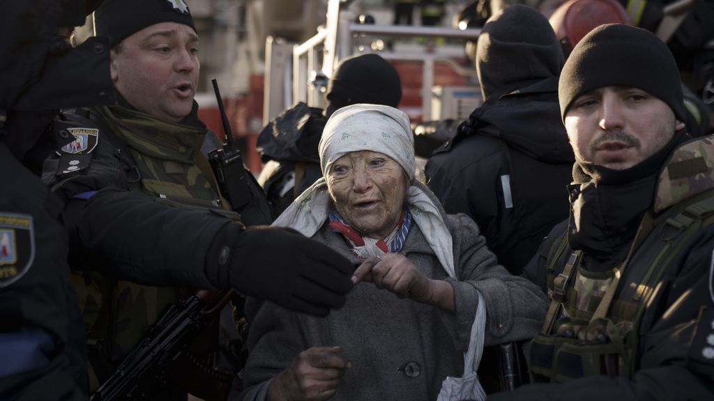 Seorang wanita tua dibantu polisi setelah diselamatkan oleh petugas pemadam kebakaran dari dalam apartemennya setelah pengeboman di Kiev, Ukraina, Selasa (15/3/2022). 