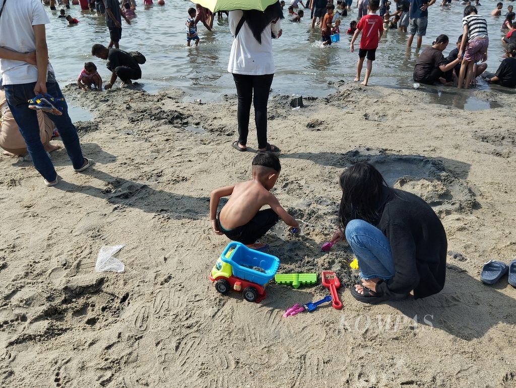 Dua anak bermain pasir di Pantai Lagoon, Ancol, Jakarta Utara, Kamis (11/4/2024) siang.