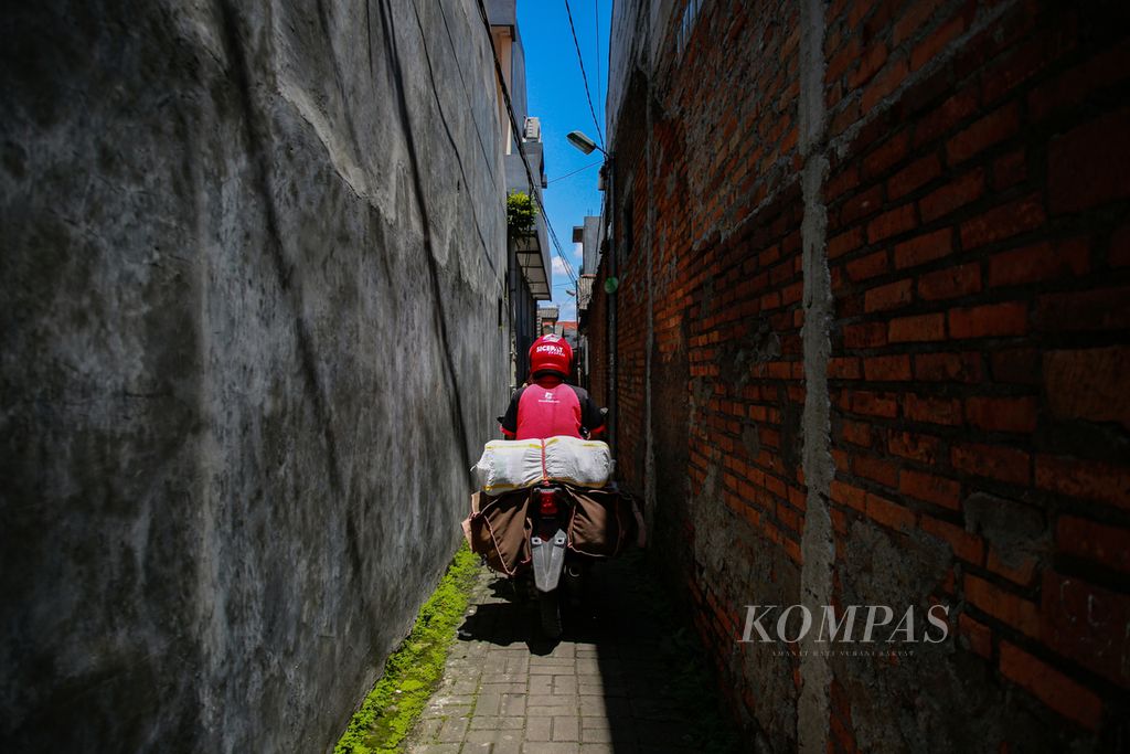 Kurir paket SiCepat, Andika menembus jalan-jalan tikus untuk mengantarkan paket ke pelanggan di kawasan Parung Serab, Ciledug, Kota Tangerang, Banten, Rabu (6/4/2022).  
