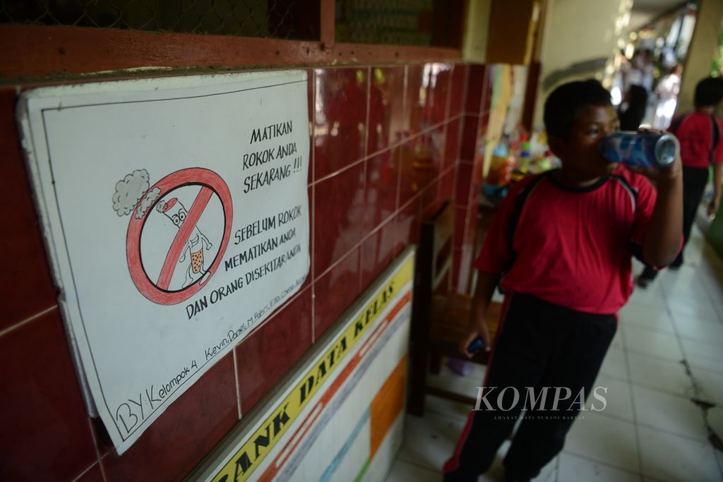 Murid beristirahat di dekat poster buatan temannya yang berisi informasi bahaya rokok di SD Negeri Tugu, Jebres, Solo, Jawa Tengah, 2019. 