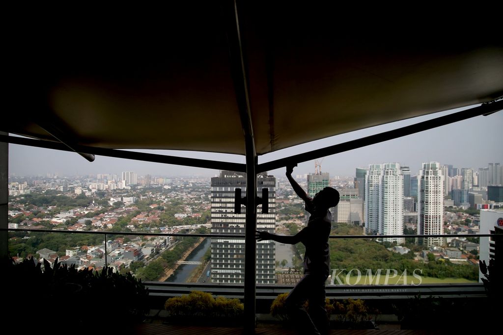 Petugas kebersihan bekerja dengan latar belakang kompleks perkantoran dengan ruang terbuka hijau di kawasan Sudirman, Jakarta, Kamis (19/9/2019). Berdasarkan Peraturan Daerah DKI Jakarta Nomor 1 Tahun 2012 tentang Rencana Tata Ruang Wilayah 2030, Jakarta menargetkan total luas ruang terbuka hijau mencapai 30 persen dari luas wilayah DKI pada tahun 2030.  