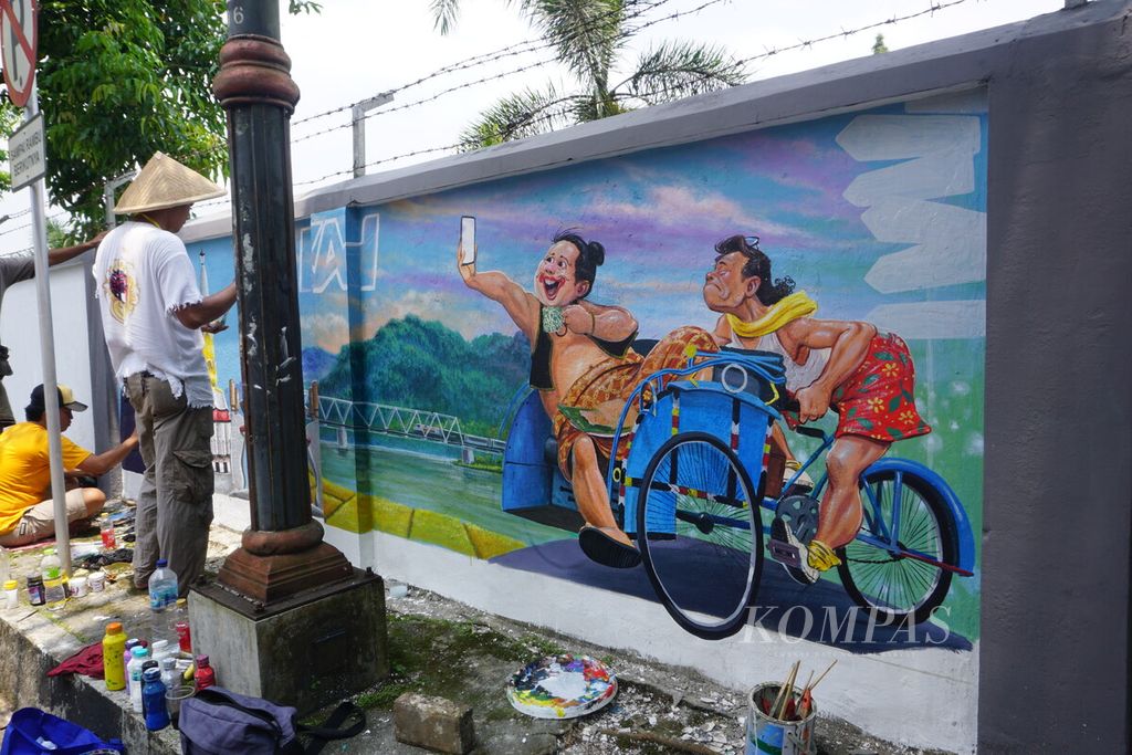 Para seniman mural sedang menyelesaikan lukisan aneka ikon khas Banyumas di tembok dinding area Stasiun Purwokerto, Banyumas, Jawa Tengah, Selasa (29/3/2022).