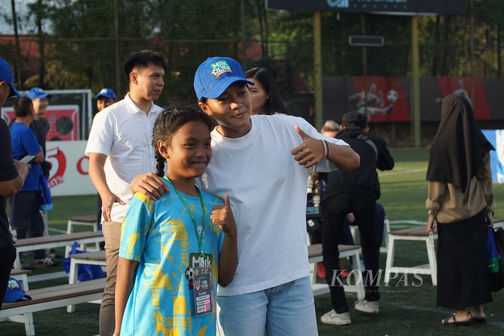 Siswi SDN 036 Ujungberung, Kartika Ifra (12), berfoto bersama pemain timnas sepak bola putri, Reva Octaviani, setelah gelaran turnamen sepak bola putri antarsekolah dasar dan madrasah ibtidaiyah, MilkLife Soccer Challenge, di lapangan Progresif Sport Center, Bandung, Jawa Barat, Minggu (23/6/2024).