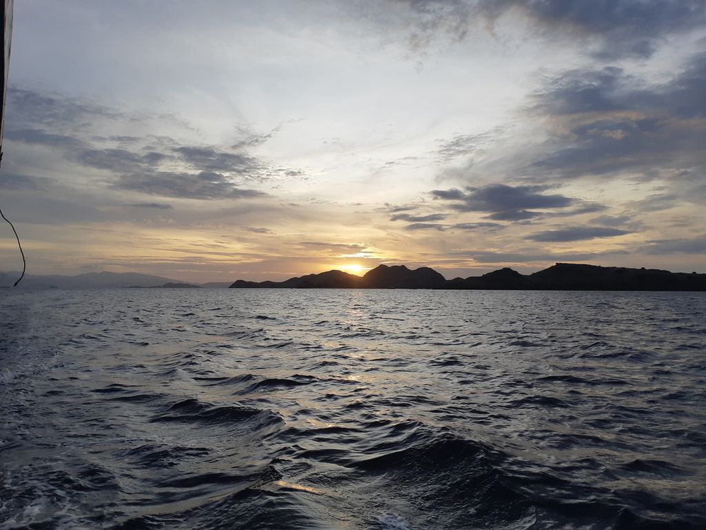 Matahari terben di balik Pulau Komodo, Kabupaten Manggarai Barat, NTT, pada Jumat (24/6/2022). Pada sore itu, gelombang laut semakin tinggi.