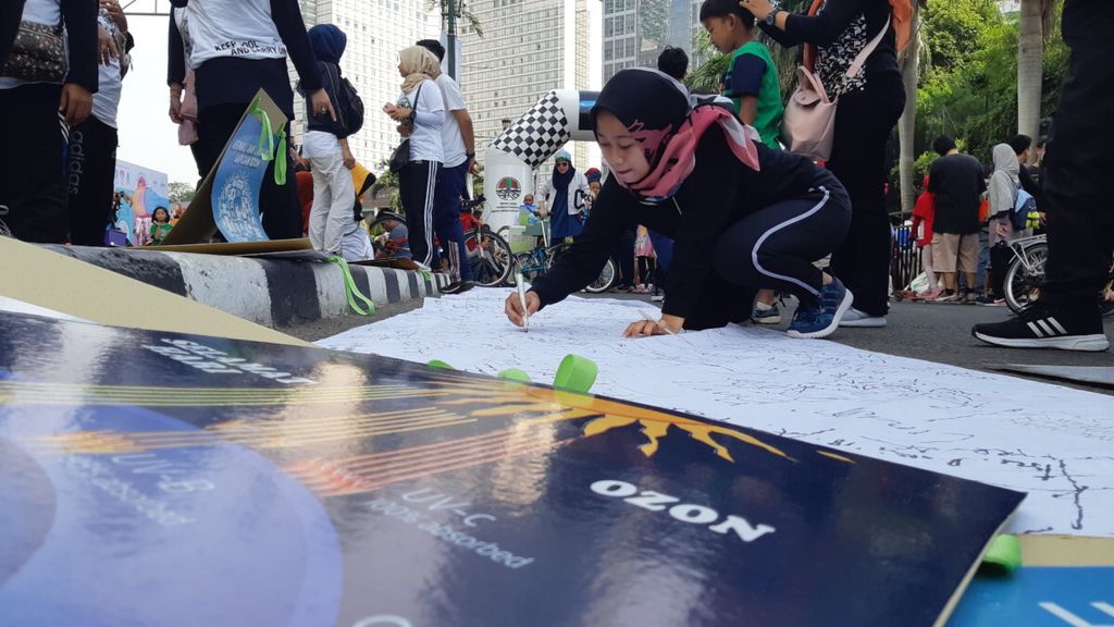 Orang yang ada di kawasan <i>car free day</i> di Jalan Imam Bonjol, Jakarta, menandatangani dukungan untuk menjaga lapisan ozon pada perayaan Hari Ozon Internasional, Minggu (16/9/2018).