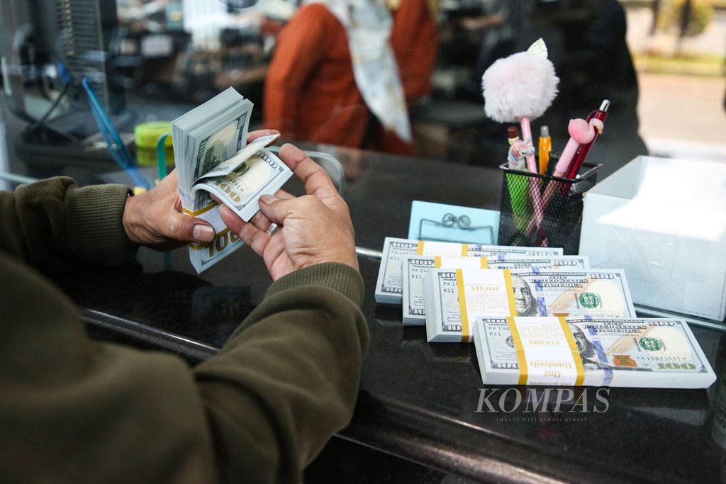 A customer inspects US dollars purchased at the PT Valuta Inti Prima foreign exchange bureau in Cikini, Jakarta on Monday (20/11/2023).