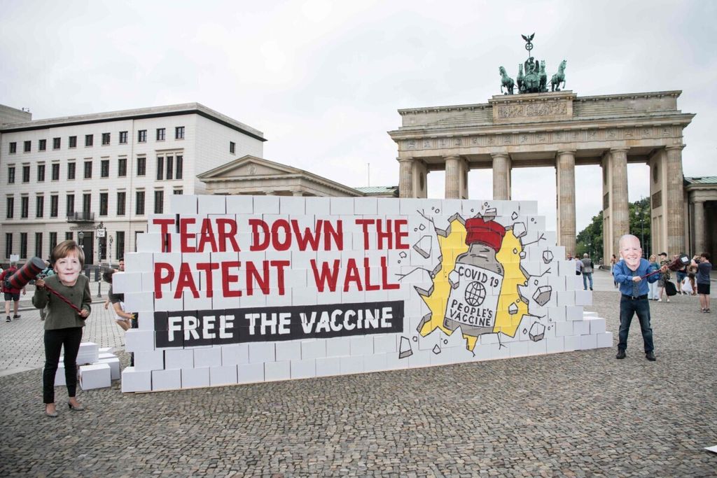 Para pegiat mengenakan topeng Kanselir Jerman Angela Merkel dan Presiden Amerika Serikat Joe Biden berunjuk rasa di Berlin, Jerman, tanggal 14 Juli 2021. mereka meminta negara-negara maju menangguhkan paten vaksin Covid-19 agar bisa diakses secara global. 