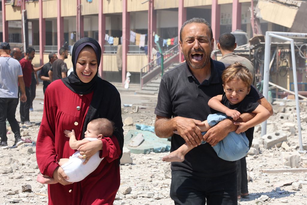 Warga Palestina menggendong anak-anak mereka setelah serangan Israel menyasar sekolah yang menampung warga Palestina yang mengungsi di Rimal, pusat Kota Gaza, Melasa (20/8/2024).