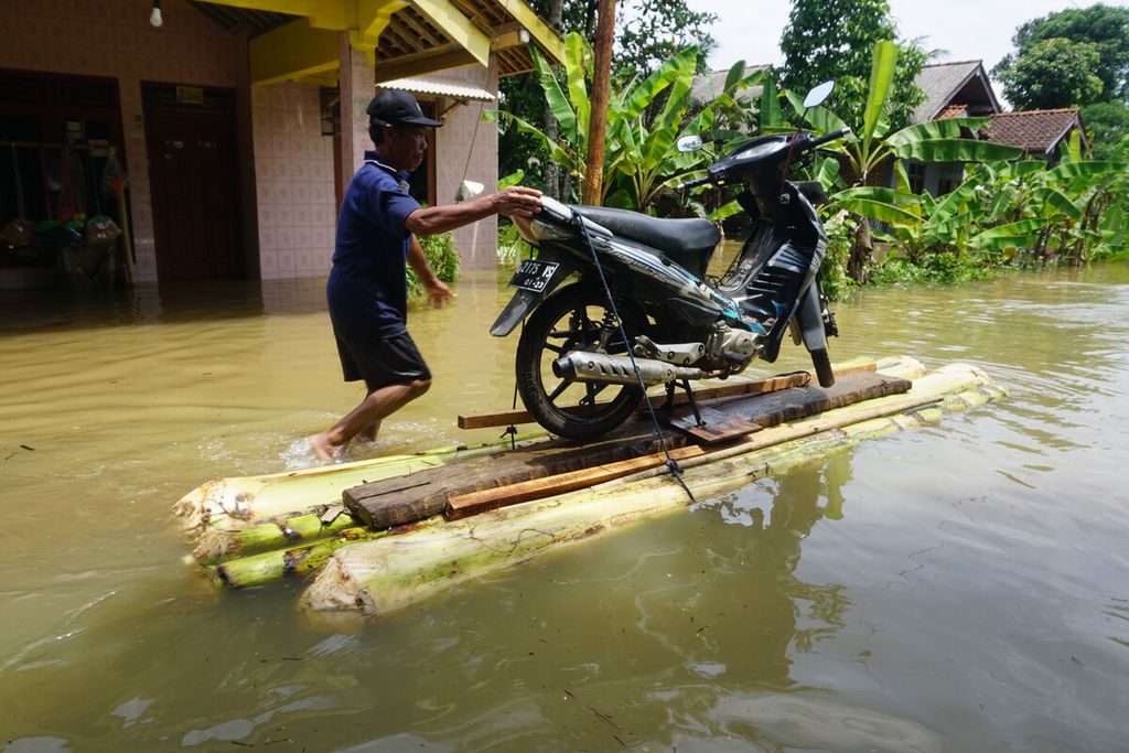 Banjir merendam Desa Nusadadi, Kecamatan Sumpiuh, Banyumas, Jawa Tengah, Jumat (18/3/2022). Sekitar 20 warga mengungsi ke tempat aman. Tampak warga mengevakuasi sepeda motornya.