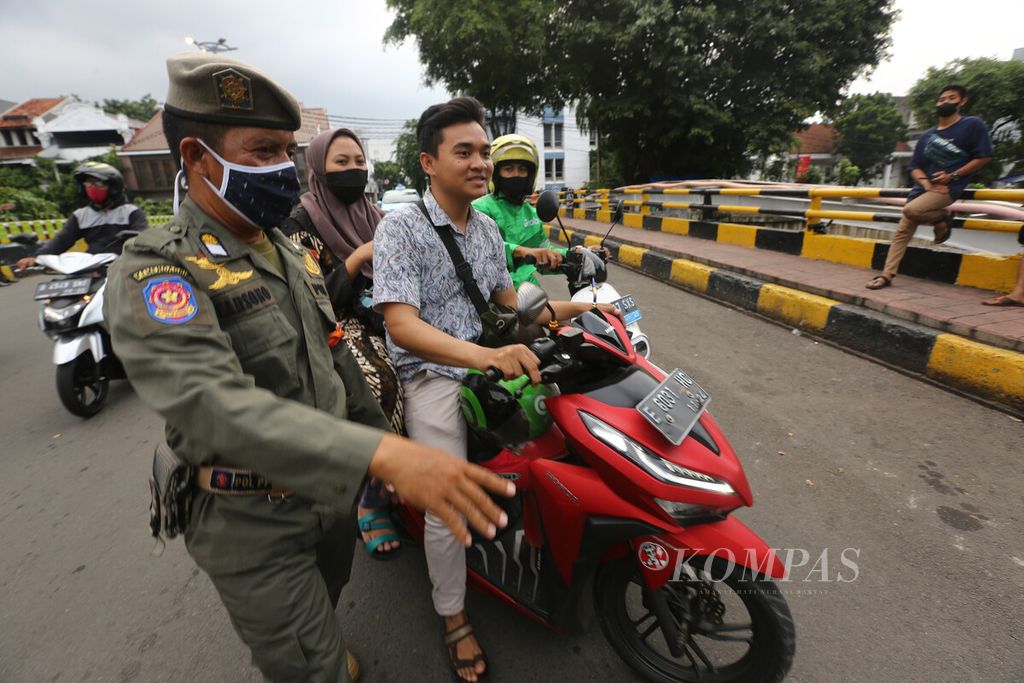 Petugas Satpol PP menghentikan pengguna jalan yang tidak mengenakan masker saat berlangsung operasi protokol kesehatan di kawasan Kota Tua, Taman Sari, Jakarta Barat, Selasa (/2/2022). Operasi protokol kesehatan terus digalakkan untuk menertibkan masyarakat yang belum disipli prptokol kesehatan.