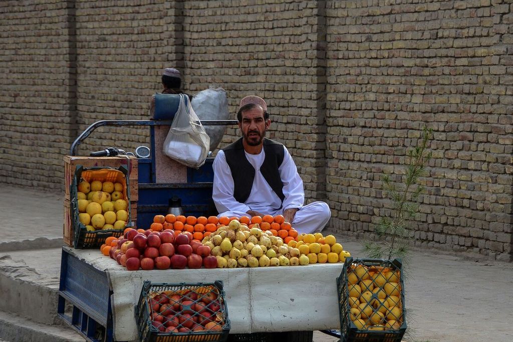 Seorang pedagang buang tengah menunggung pembeli di sebuah jalam di Kandahar pada Sabtu (12/3/2022).