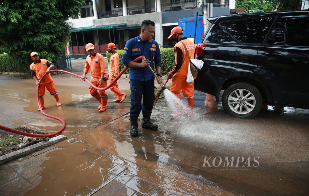 Petugas pemadam kebakaran serta penanganan prasarana dan sarana umum (PPSU) bergotong royong membersihkan lumpur sisa banjir di jalur pedesterian Jalan Kemang Raya, Jakarta Selatan, Rabu (5/10/2022). 