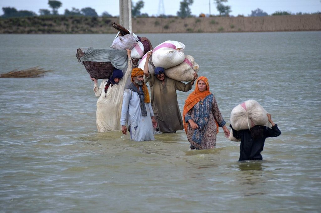 Satu keluarga pengungsi menerobos banjir setelah hujan deras turun di Distrik Jaffarabad, Provinsi Baluchistan, barat daya Pakistan, Rabu (24/8/2022). Otoritas Penanggulangan Bencana Nasional Pakistan menyatakan 126 orang tewas dalam insiden terkait banjir dalam 48 jam terakhir. Sebagian besar korban adalah perempuan dan anak-anak.