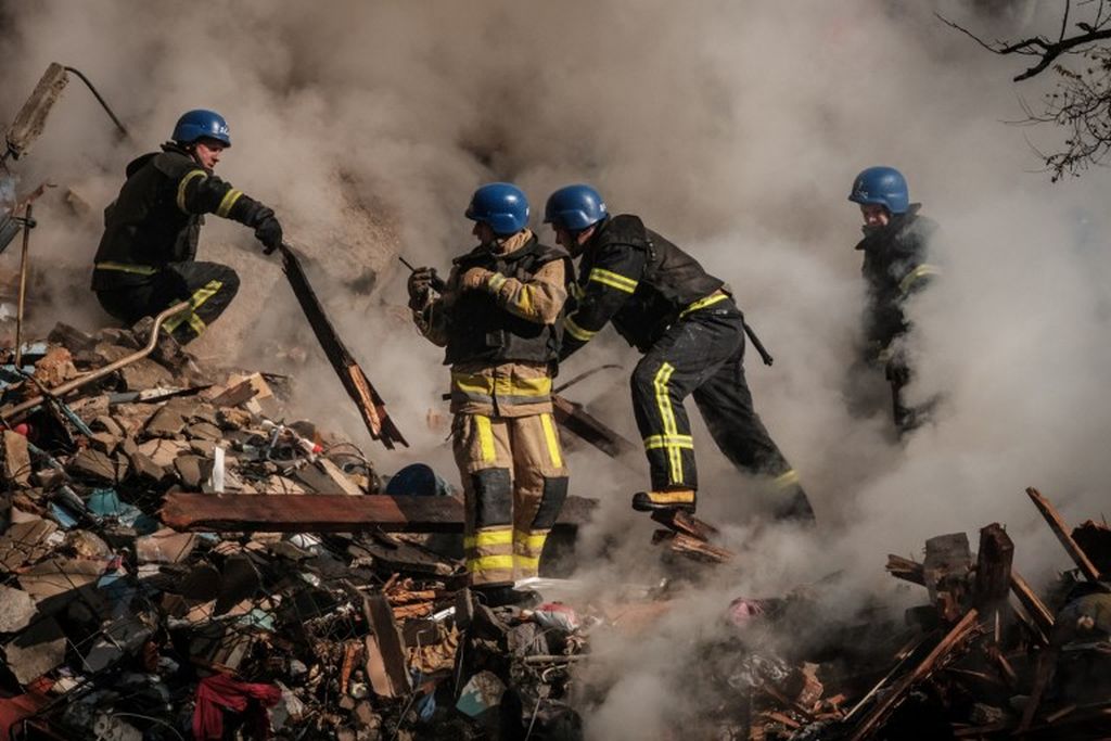  Pemadam kebakaran mencari korban selepas serangan Rusia ke sejumlah lokasi di Kyiv, Ukraina pada 17 Oktober 2022. Sejak Jembatan Kerch diledakkan pada 8 Oktober 2022, Rusia meningkatkan serangan ke Ukraina. 