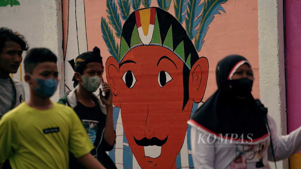 Warga melintasi mural menyambut HUT Ke-495 DKI Jakarta di Palmeriam, Matraman, Jakarta Timur, Minggu (19/6/2022). 
