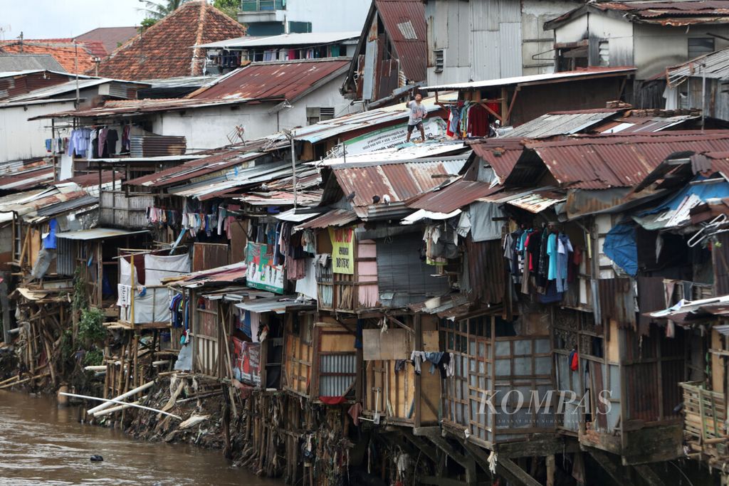 Seorang anak bermain layang-layang di atas rumah di pinggir Sungai Ciliwung, Matraman, Jakarta Timur, Jumat (7/2/2020). 